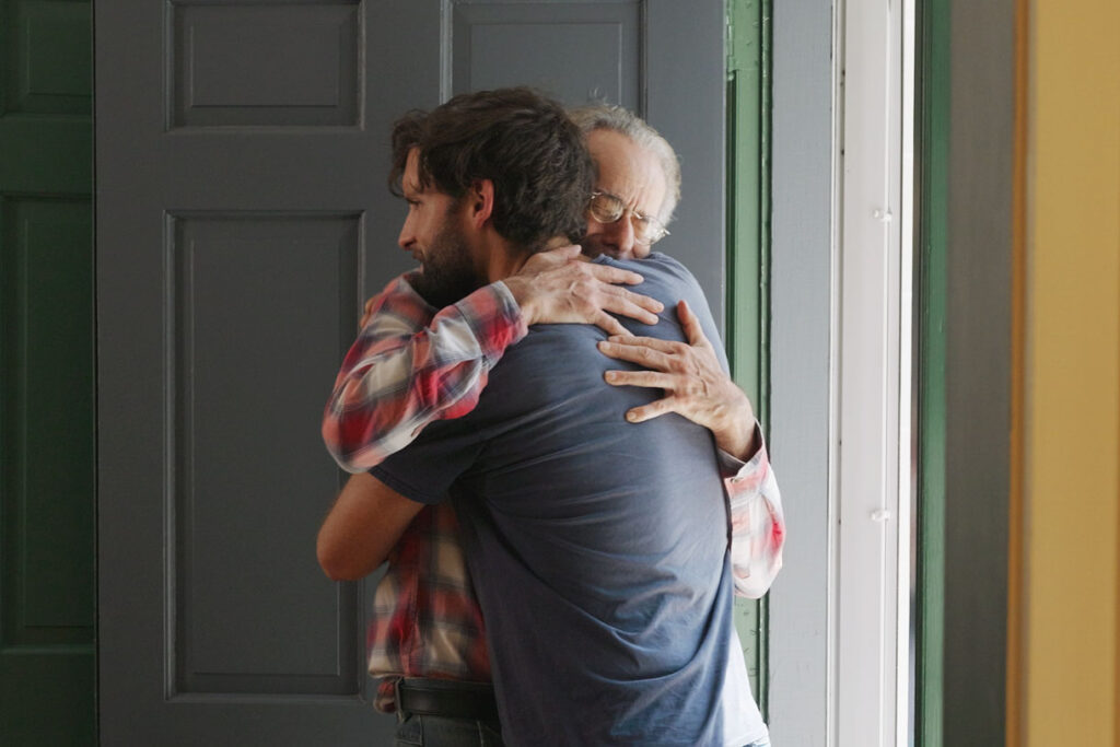 Older father and son embracing in doorway