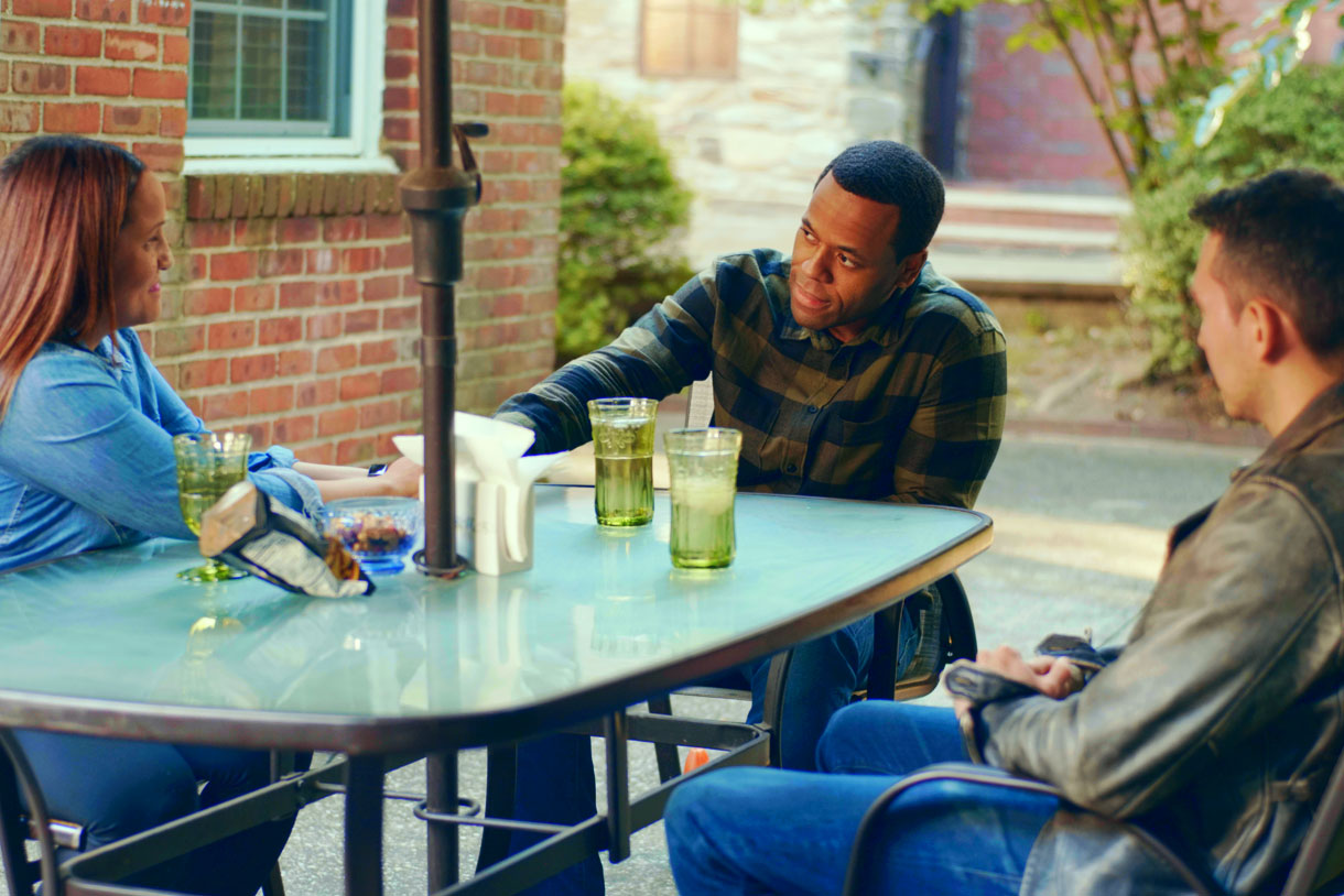 A woman and two men talking around a table